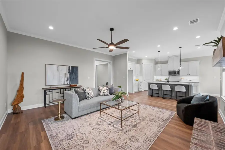 Living room with crown molding, dark wood-style flooring, recessed lighting, and a ceiling fan Living room with crown molding, dark wood-style flooring, recessed lighting, and a ceiling fan
