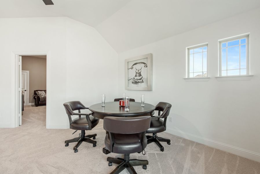 Bonus room with round table, four rolling chairs, vaulted ceiling, and carpet flooring