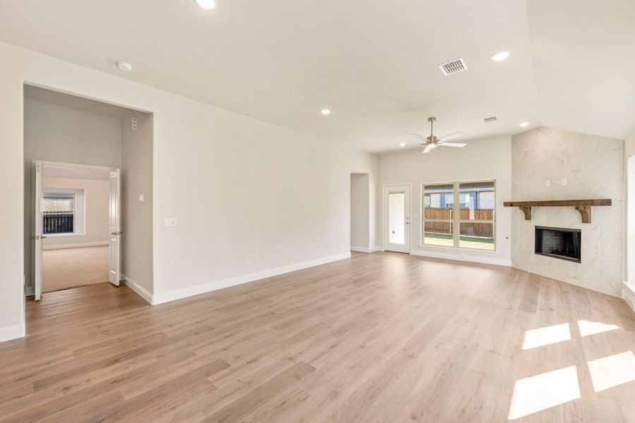 Open living room with hardwood floors, stone fireplace, ceiling fan, and sliding glass doors to backyard Open living room with hardwood floors, stone fireplace, ceiling fan, and sliding glass doors to backyard
