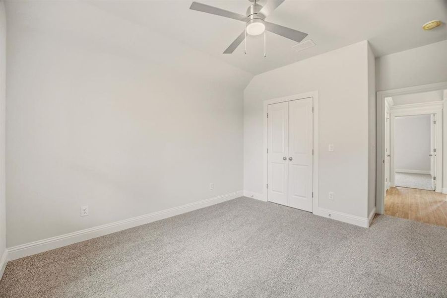 Unfurnished bedroom featuring light colored carpet, a closet, a ceiling fan, and vaulted ceiling Unfurnished bedroom featuring light colored carpet, a closet, a ceiling fan, and vaulted ceiling