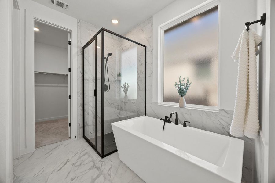 Bathroom with light marble finish flooring, a marble finish shower, recessed lighting, a freestanding bath, and a walk in closet