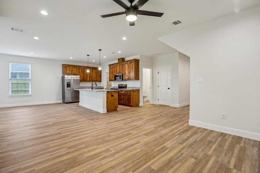 Kitchen with wood-style vinyl flooring, stainless steel appliances, open floor plan, baseboards, and visible vents