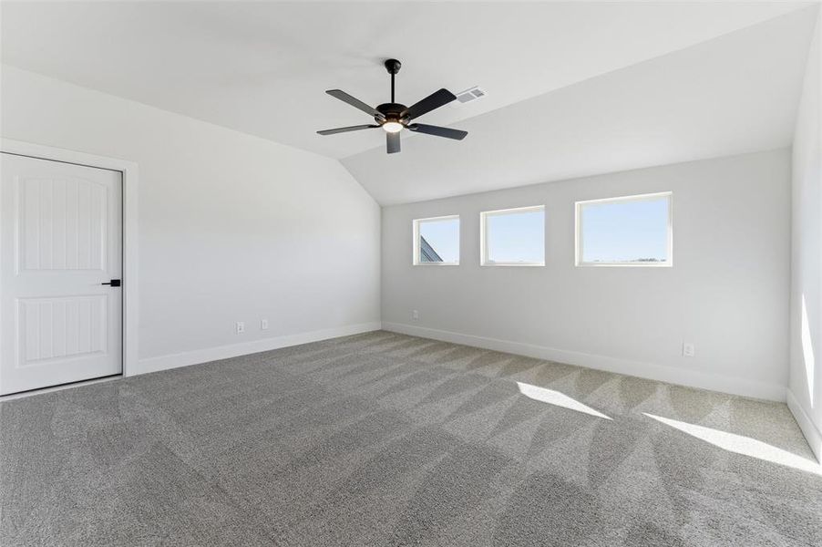 Unfurnished room with lofted ceiling, light carpet, and a ceiling fan