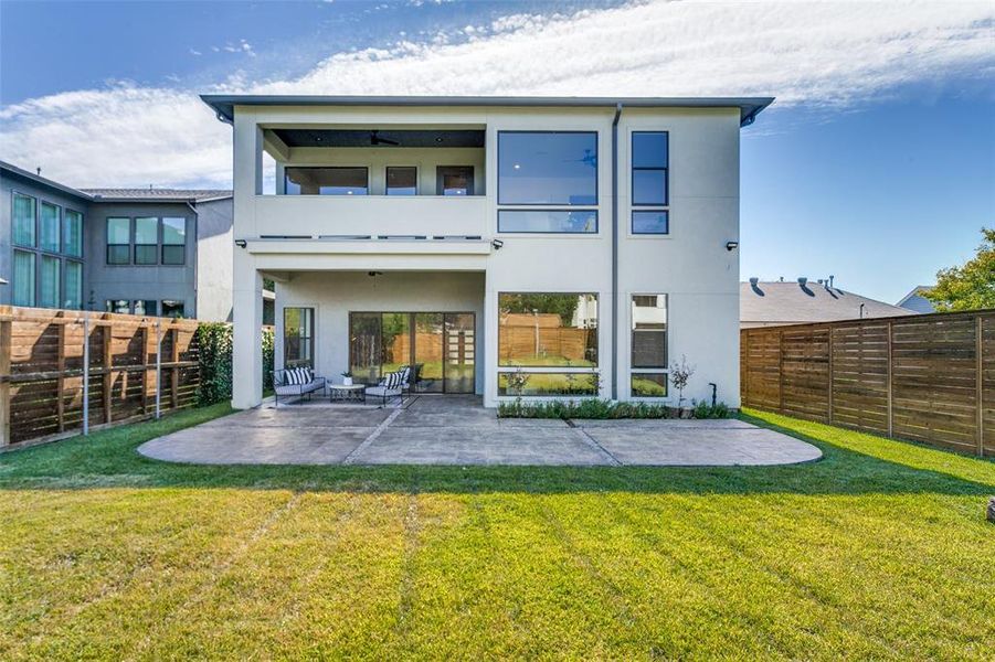 Rear view of property featuring a patio, a yard, and a balcony