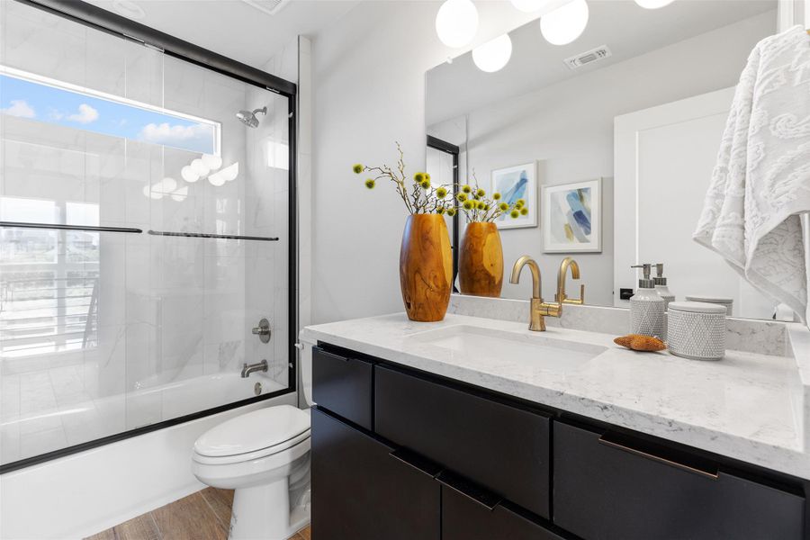 Full bath with enclosed tub / shower combo, vanity, and light wood finished floors
