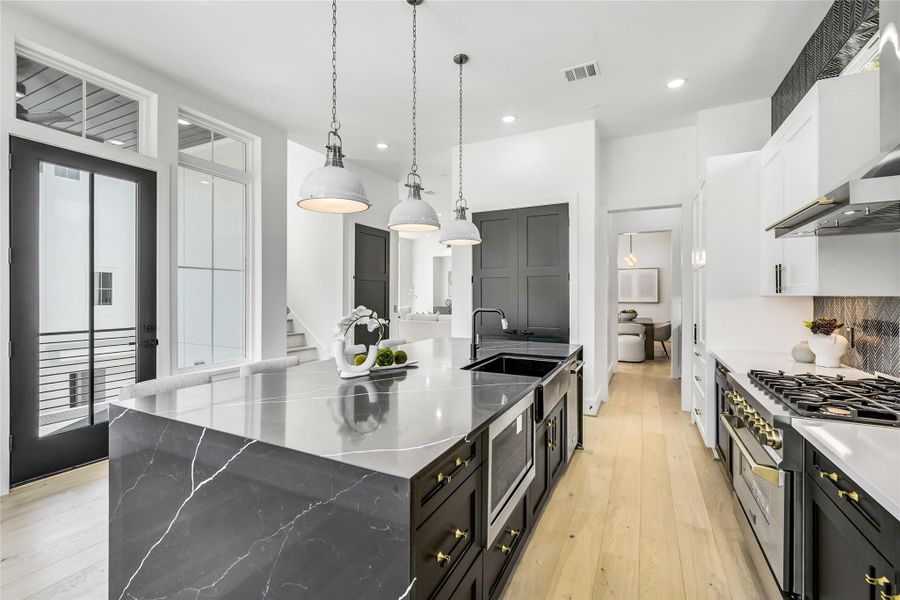 Soaring ceilings and abundant natural light define this culinary space, where form meets function. The kitchen showcases integrated high-end appliances, double pantries, designer pendant lighting, and a deep farmhouse sink positioned within the island for optimal workflow. French doors open to an airy balcony—ideal for morning coffee before rounds or unwinding in the evening breeze. Soaring ceilings and abundant natural light define this culinary space, where form meets function. The kitchen showcases integrated high-end appliances, double pantries, designer pendant lighting, and a deep farmhouse sink positioned within the island for optimal workflow. French doors open to an airy balcony—ideal for morning coffee before rounds or unwinding in the evening breeze.