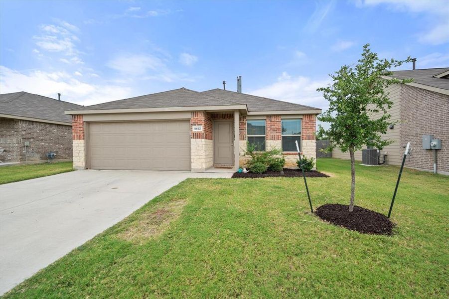 View of front of home with brick siding, an attached garage, roof with shingles, concrete driveway, and a front yard
