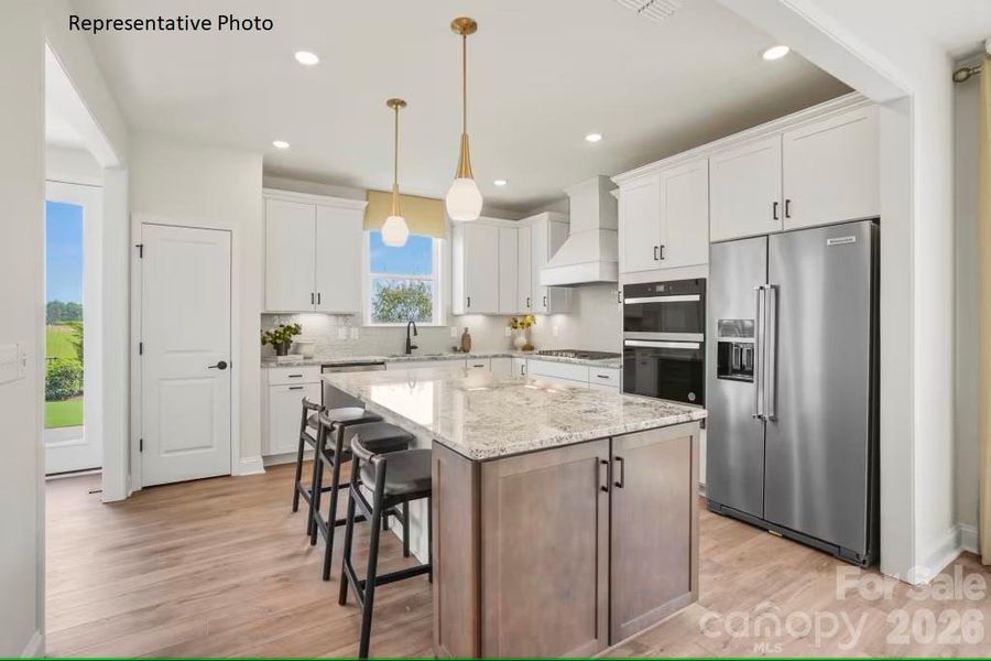 Storage-rich gourmet kitchen, featuring a large island, KitchenAid appliances, gas cooktop, and designer finishes