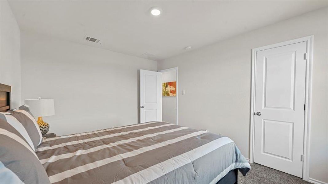 This bedroom features light gray walls, a textured gray carpet, and two white paneled doors This bedroom features light gray walls, a textured gray carpet, and two white paneled doors