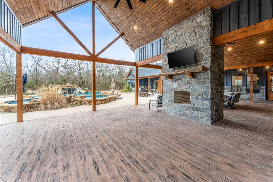 View of patio / terrace with an outdoor stone fireplace, an outdoor pool, ceiling fan, and outdoor dining area