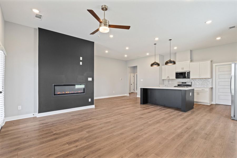 Two tone kitchen featuring open floor plan, an island with sink, dual tone cabinetry, a ceiling fan, and stainless steel appliances