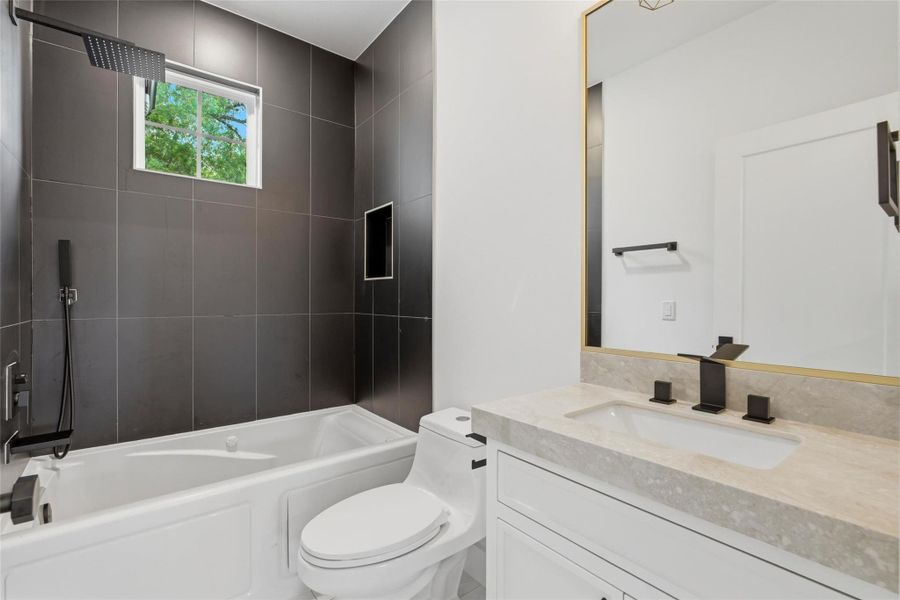 One of two secondary bathrooms located on the second floor, featuring elegant porcelain countertops and a jetted Jacuzzi tub with a convenient handheld showerhead.