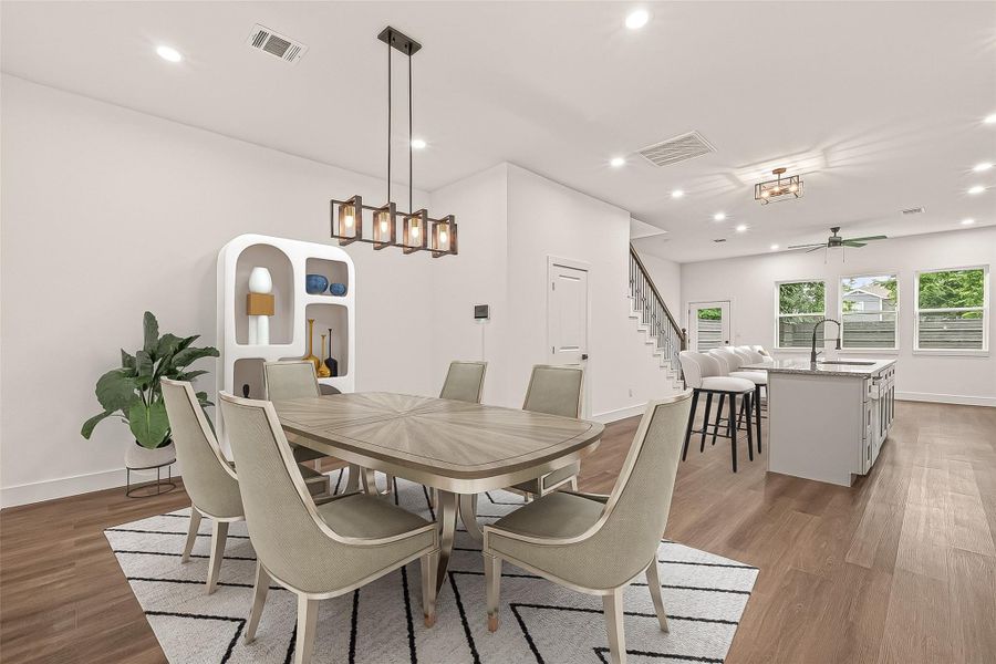 This photo showcases a modern, open-concept dining and kitchen area with elegant lighting fixtures, sleek engineer wood flooring, and large windows allowing natural light. The kitchen features an island with bar seating, and the dining area is stylishly furnished, providing a warm and inviting atmosphere.- Virtual Staging This photo showcases a modern, open-concept dining and kitchen area with elegant lighting fixtures, sleek engineer wood flooring, and large windows allowing natural light. The kitchen features an island with bar seating, and the dining area is stylishly furnished, providing a warm and inviting atmosphere.- Virtual Staging