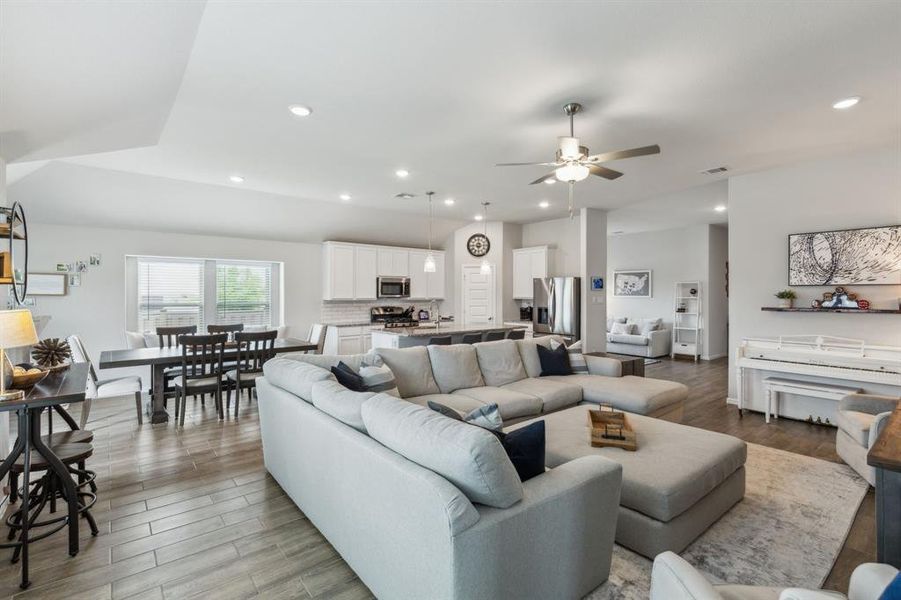 Living area featuring open floorplan to kitchen, recessed lighting, ceiling fan and light wood-like tile with view of the flex room Living area featuring open floorplan to kitchen, recessed lighting, ceiling fan and light wood-like tile with view of the flex room