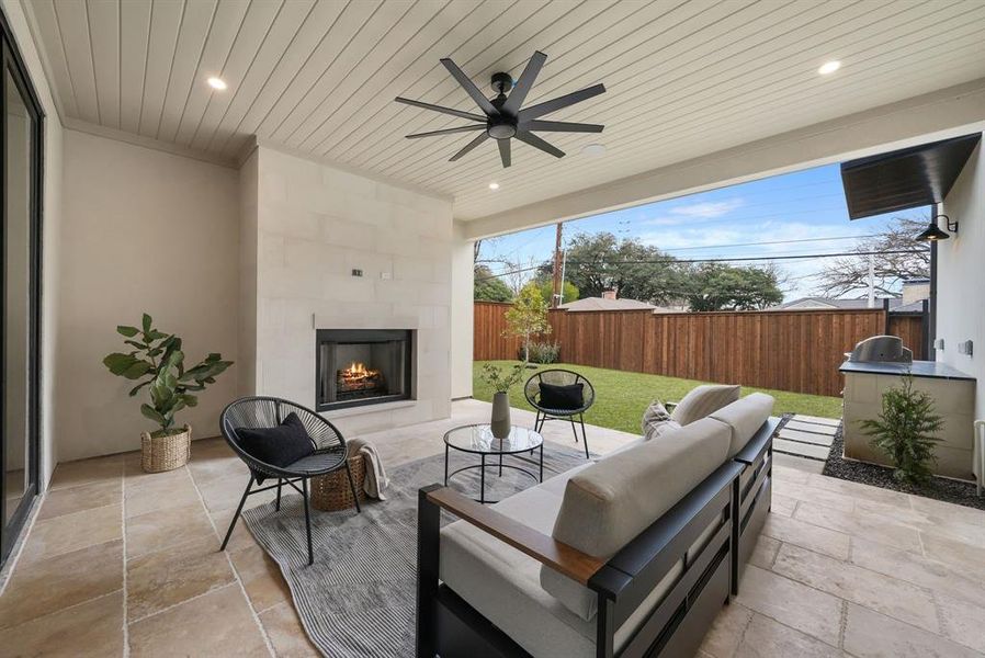 Fenced backyard with a patio area, an outdoor living space with a fireplace, and ceiling fan Fenced backyard with a patio area, an outdoor living space with a fireplace, and ceiling fan