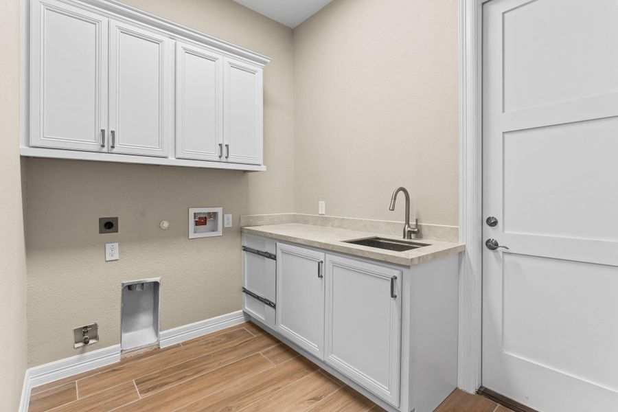 Spacious laundry room with built-in cabinetry, utility sink, and plenty of countertop space for folding.