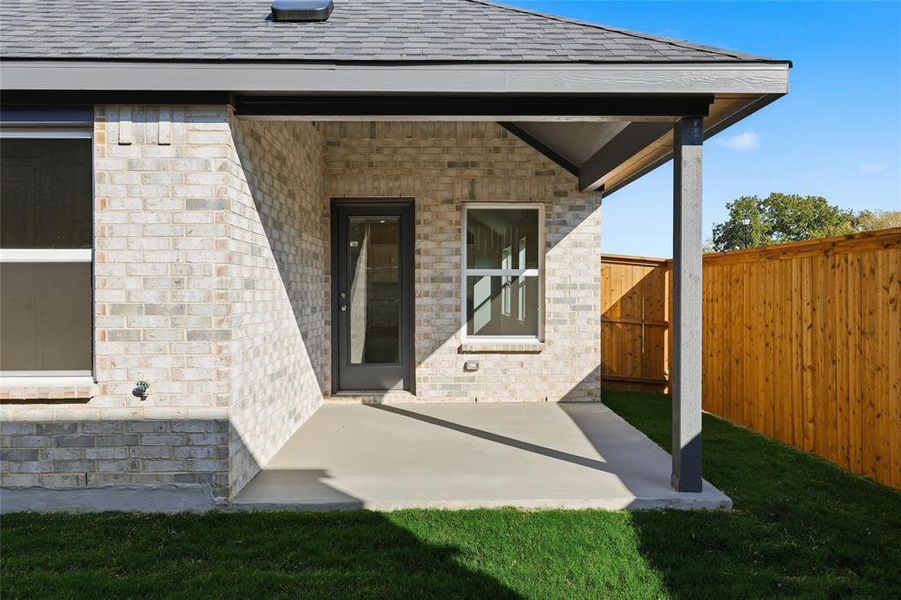 View of exterior entry with a patio area, roof with shingles, and brick siding View of exterior entry with a patio area, roof with shingles, and brick siding