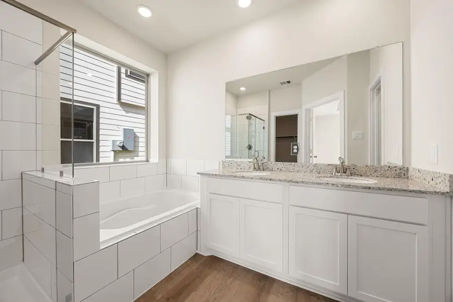 This elegant primary bath features a soaking tub, separate glass-enclosed shower, and dual vanities with ample counter space. Soft natural light and modern finishes create a clean, refreshing atmosphere. This elegant primary bath features a soaking tub, separate glass-enclosed shower, and dual vanities with ample counter space. Soft natural light and modern finishes create a clean, refreshing atmosphere.