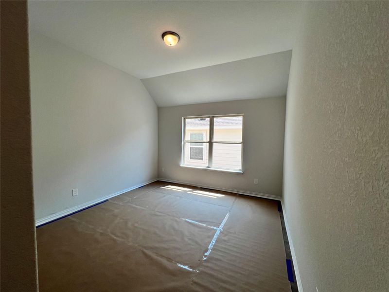 Carpeted empty room with baseboards and vaulted ceiling