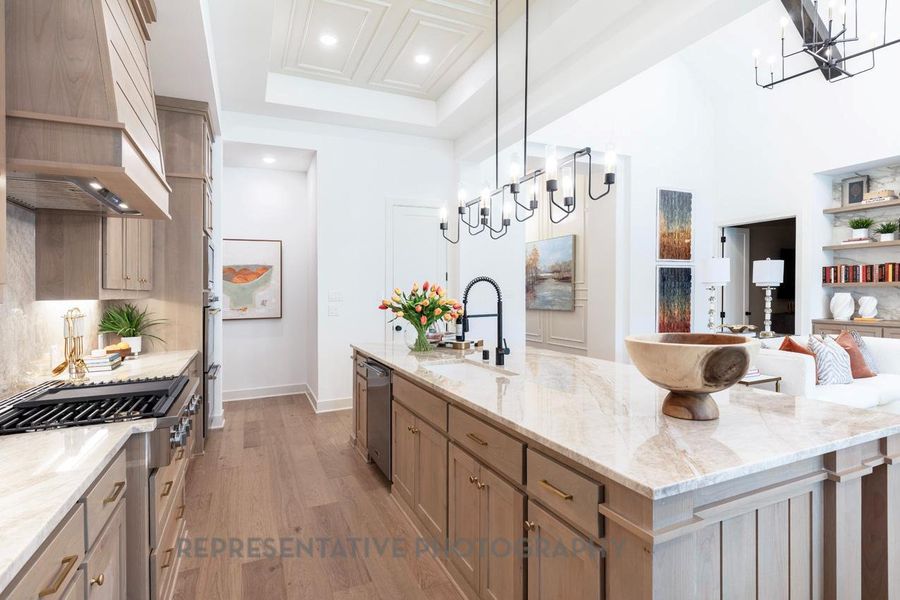 Kitchen with a chandelier, light wood-type flooring, recessed lighting, a large island with sink, and custom exhaust hood Kitchen with a chandelier, light wood-type flooring, recessed lighting, a large island with sink, and custom exhaust hood