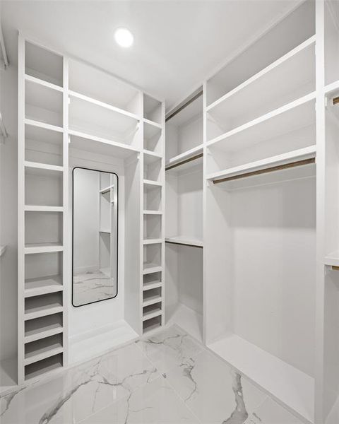 Custom-built closet featuring extensive white shelving, multiple hanging rods, dedicated shoe storage, and a full-length mirror