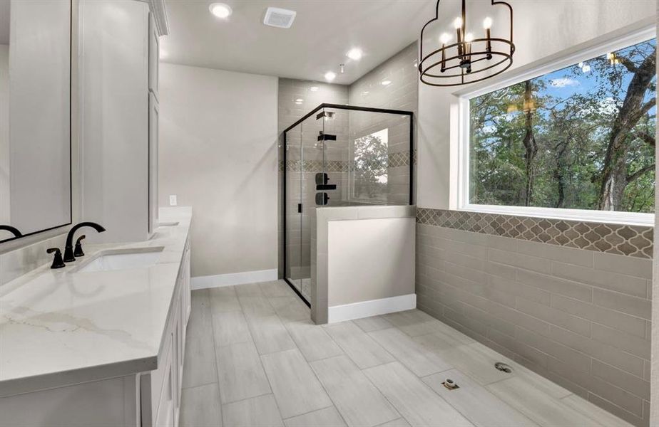 Full bath with double vanity, a stall shower, recessed lighting, and a chandelier