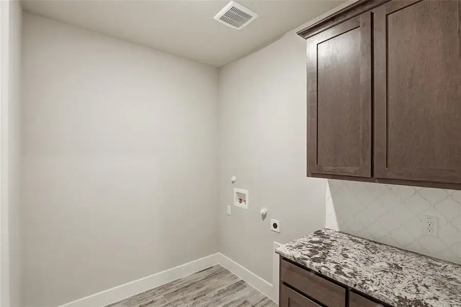 Washroom with washer hookup, light wood finished floors, electric dryer hookup, cabinet space, and gas dryer hookup