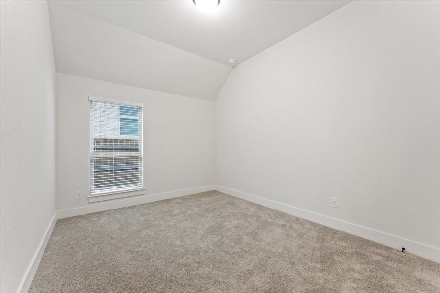 Carpeted room featuring a single window with blinds, white walls, and a sloped ceiling