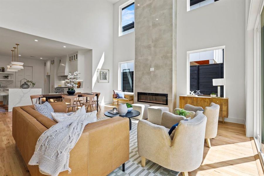 Living room featuring light wood-type flooring, a large fireplace, and a towering ceiling