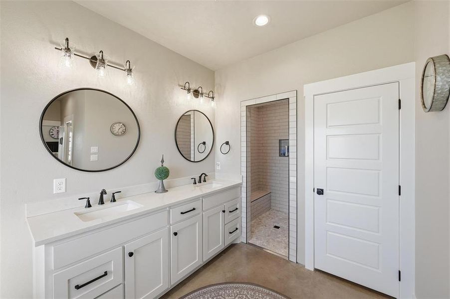 Primary Bathroom with double vanity, a walk in shower, recessed lighting, and finished concrete floors Primary Bathroom with double vanity, a walk in shower, recessed lighting, and finished concrete floors