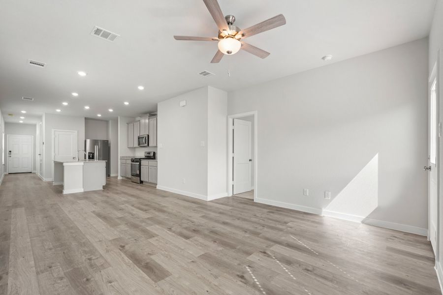 A large empty room with a ceiling fan and a wood floor. A large empty room with a ceiling fan and a wood floor.