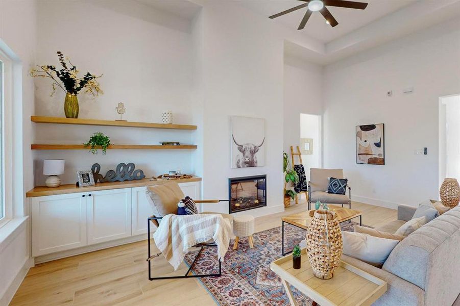 Living room featuring a towering ceiling, light hardwood / wood-style floors, and ceiling fan