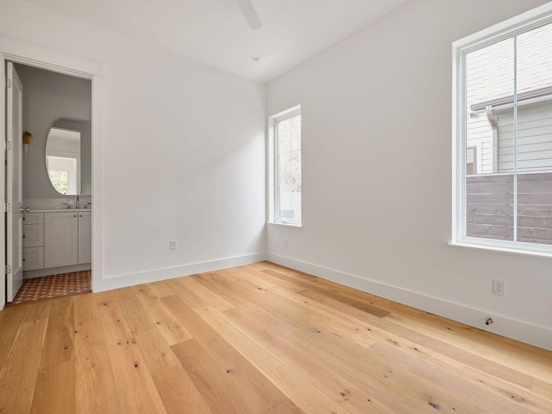 Unfurnished bedroom with light wood finished floors, ceiling fan, and ensuite bath Unfurnished bedroom with light wood finished floors, ceiling fan, and ensuite bath