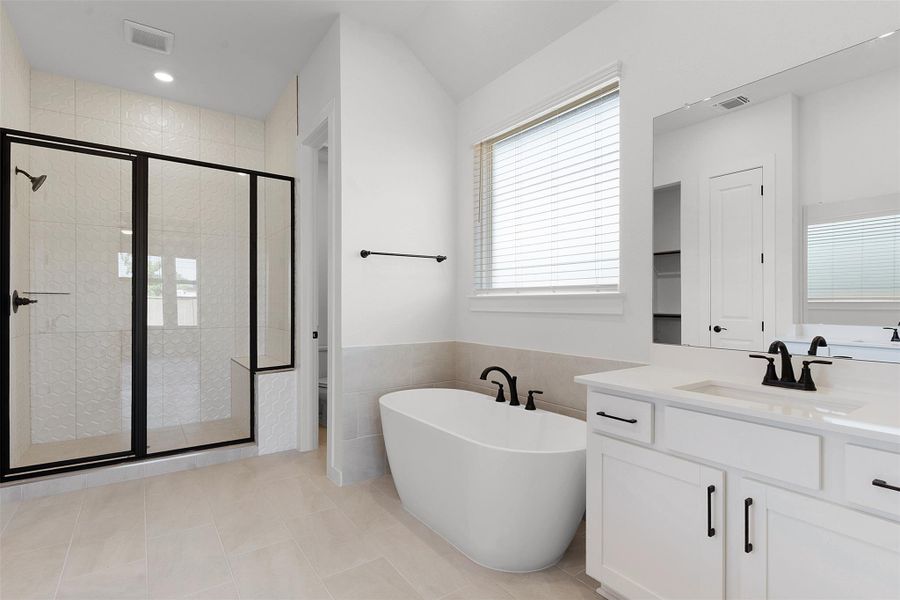 Bathroom with a shower stall, a freestanding tub, vanity, tile walls, and light tile patterned flooring