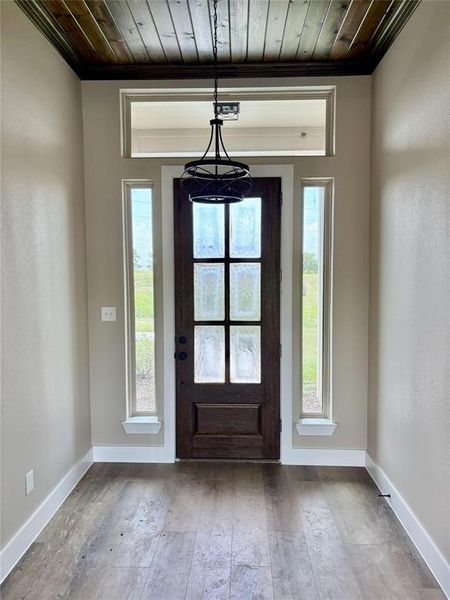 Foyer entrance featuring wooden ceiling, hardwood / wood-style floors, ornamental molding, and plenty of natural light