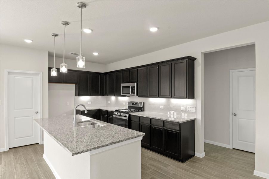 Kitchen with stainless steel appliances, light wood-style flooring, light stone counters, and recessed lighting
