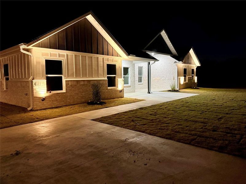 View of front facade with brick siding, board and batten siding, and a lawn
