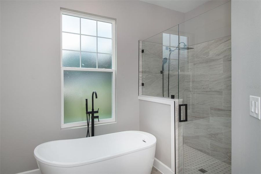 Soak tub and tiled walk-in shower area with glass enclosure. The window add great natural light while providing privacy