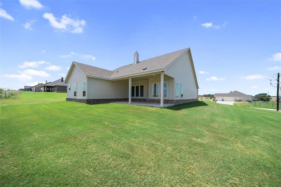 Rear view of house with roof with shingles, a patio, a chimney, and a lawn Rear view of house with roof with shingles, a patio, a chimney, and a lawn