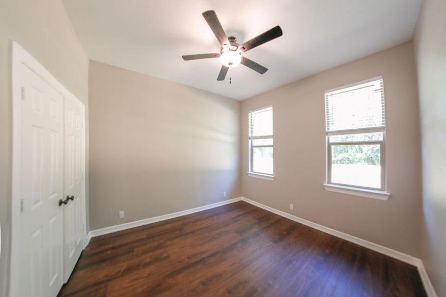 Empty room with dark wood-style floors and ceiling fan Empty room with dark wood-style floors and ceiling fan