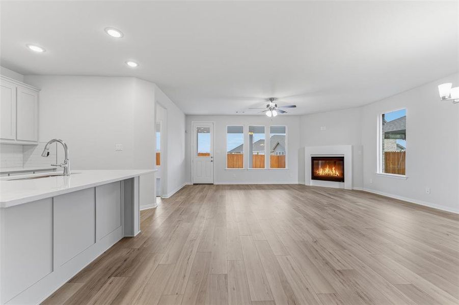 Unfurnished living room with light wood-style flooring, a glass covered fireplace, plenty of natural light, recessed lighting, and ceiling fan