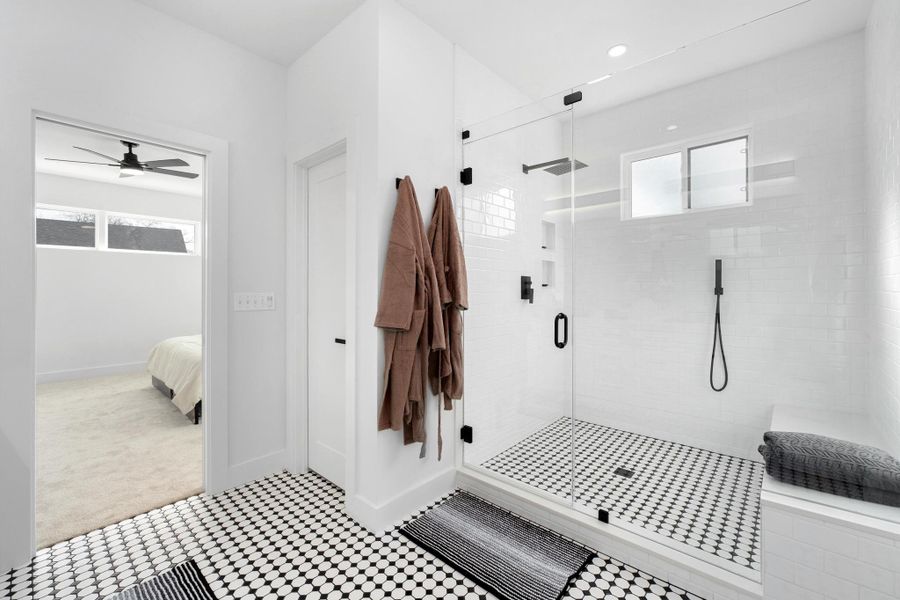 Ensuite bathroom featuring healthy amount of natural light, a stall shower, ceiling fan, and light colored carpet
