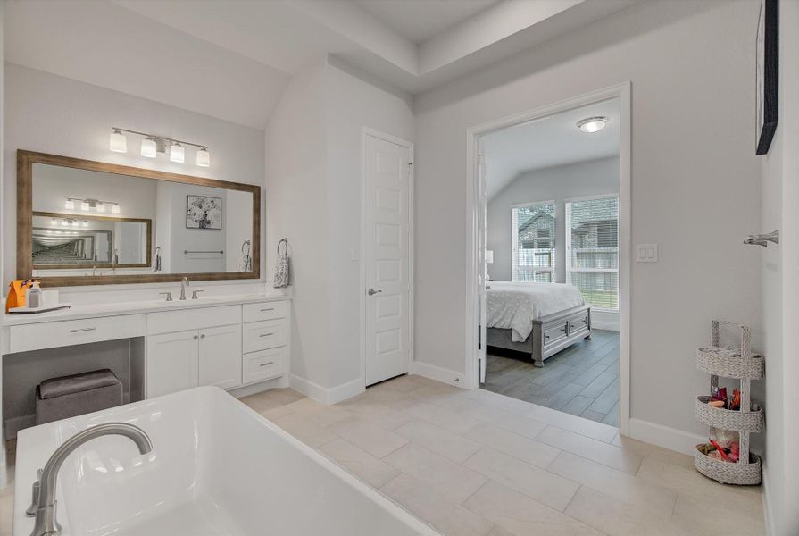 This impressive primary bathroom offers 11' ceilings, stylish French doors connecting to the primary bedroom, and a beautifully detailed tray ceiling with recessed lighting.