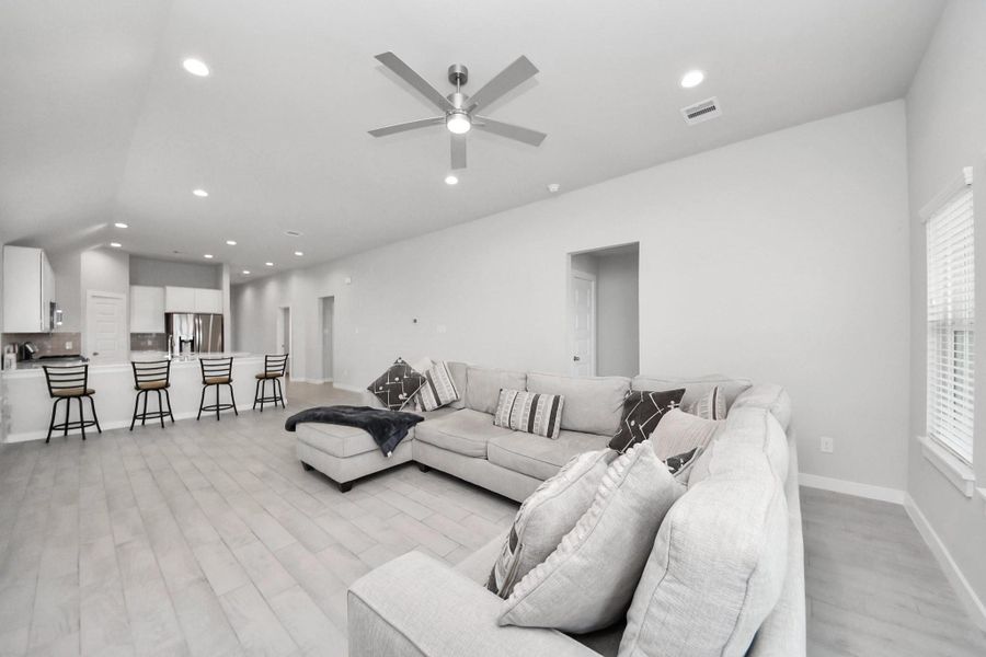 Living room with soaring ceilings, recessed lighting, and an open layout that connects seamlessly to the kitchen and dining areas, creating a bright and inviting gathering space.