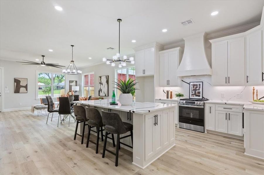 Kitchen featuring stainless steel gas range, premium range hood, chandelier, white cabinets, eat a kitchen, etc. Kitchen featuring stainless steel gas range, premium range hood, chandelier, white cabinets, eat a kitchen, etc.