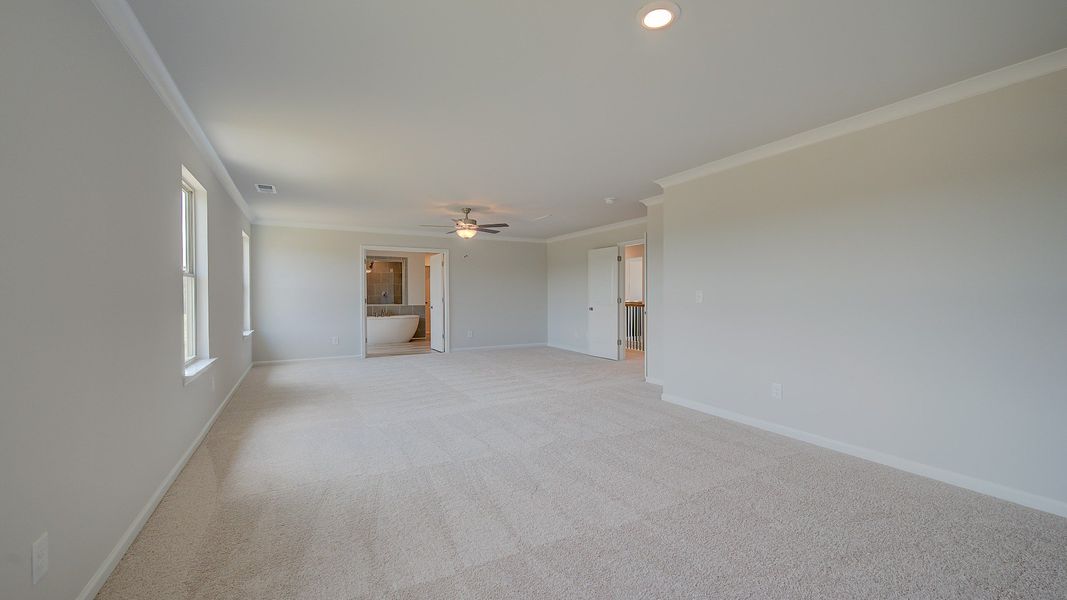 Spacious primary suite with sitting room, carpet flooring, and natural light in the Clarity at Brighton in Locust Grove, GA.