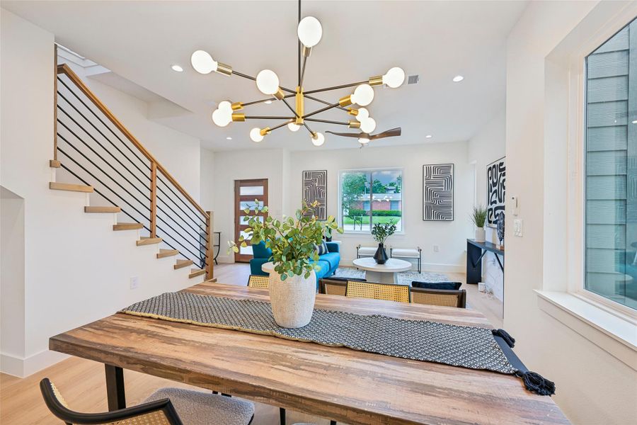 A striking modern chandelier illuminates a well-lit living area and dining space.