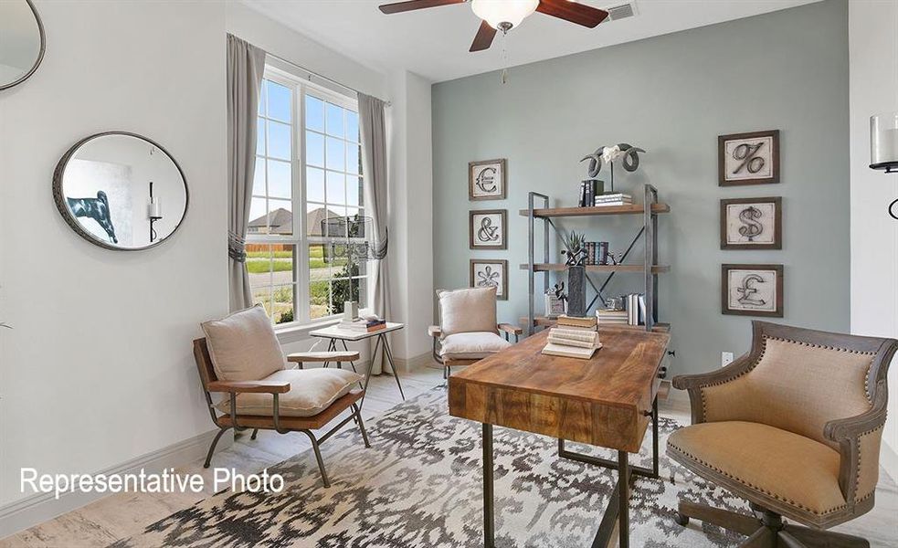Spacious room featuring a large multi-pane window, ceiling fan with integrated lighting, and light wood-finish flooring