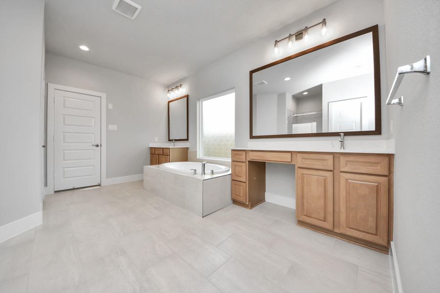 Indulge in a spa-like retreat within the confines of this primary bathroom. Delight in a spacious walk-in shower enveloped in stylish tile surround, unwind in a separate garden tub adorned with custom detailing.