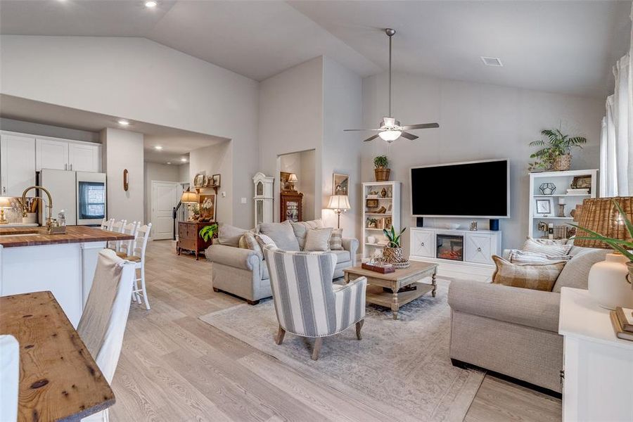 Living room featuring light wood finished floors, ceiling fan, high vaulted ceiling, and recessed lighting Living room featuring light wood finished floors, ceiling fan, high vaulted ceiling, and recessed lighting